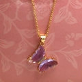 Detail of a golden necklace with a light purple crystal butterfly pendant and small stones - 1# Purple