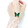 Detail of a gold butterfly necklace featuring dark green faceted crystal wings and zircons - Green