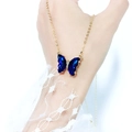 Close-up of a blue crystal butterfly necklace on a gold chain with lace sleeve detail - Dark Blue
