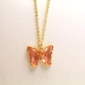 Primer plano detallado del collar mariposa dorado con alas de cristal rosa y pequeños brillantes - Collar / Champán