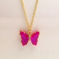 Gros plan détaillé du pendentif papillon en cristal rose sur une chaîne dorée - Collier / Rouge Prune