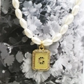 Macro detail of pearl necklace featuring a gold pendant with crystal letter G inlay - Letter G