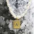 Macro shot of rectangular gold letter A pendant with pearls and colorful zircons - Letter A