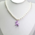 Detailed macro view of purple balloon dog pendant on elegant faux pearl necklace chain - Purple