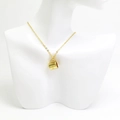 Détail d'un collier doré avec un pendentif en forme de tasse et gravure CO sur un mannequin - Or