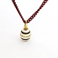 Macro detail of egg-shaped enamel pendant necklace with intricate gold trims and red cord - White Egg Red Rope Style (01)