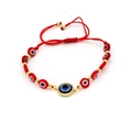 Detail of red braided Evil Eye bracelet with blue pendant and gold metal accents - Round Eye Pendant Style (O2)