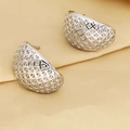 Primer plano detallado de los pendientes plateados calados sobre una elegante tela de seda - Estilo de Hemisferio de Rejilla de Diamante / Oro blanco
