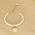 Detail of pearl bracelet with golden letter E pendant and adjustable sliding cord closure - Letter E