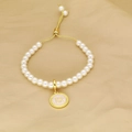 Detail of pearl bracelet featuring adjustable gold slide clasp and pink enamel letter H charm - Letter H