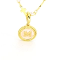 Vue macro du collier doré avec pendentif M, breloque croix et perles blanches - M