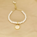 Detailed macro view of the gold K letter pendant on the adjustable pearl bracelet - Letter K