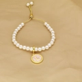 Detail view of gold adjustable clasp and white pearls with round letter L pendant - Letter L