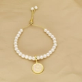 Detail of pearl bracelet featuring a pink enamel letter O pendant and gold adjustable clasp - Letter O