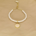 Detail of white pearl bracelet featuring a pink enamel letter P charm and golden toggle clasp - Letter P