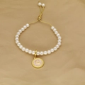 Detailed macro shot of white pearl bracelet with gold letter Q pendant and adjustable cord - Letter Q