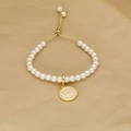 Detailed macro of a pearl bracelet featuring a gold letter R pendant and adjustable clasp - Letter R