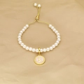 Adjustable pearl bracelet featuring a pink enamel letter S pendant and gold-tone chain - Letter S