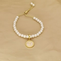 Detail view of pearl bracelet with golden letter T charm and adjustable drawstring closure - Letter T