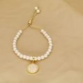 Detail showing letter U charm on pearl bead bracelet with golden adjustable chain link - Letter U