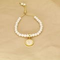 Detail of adjustable pearl bracelet with golden letter Y charm on textured paper - Letter Y