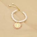 Detail of beaded pearl bracelet featuring a gold religious pendant and adjustable chain - Light Pink (C3)