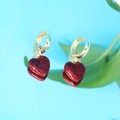 Détail de créoles dorées avec pendentifs cœur à paillettes rouges sur surface réfléchissante - Boucles d'Oreilles Pendantes Cœur