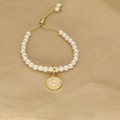 Adjustable pearl bracelet with a golden letter Z charm on a soft pink background - Letter Z
