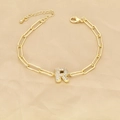 Macro detail of gold paperclip chain bracelet with a sparkling crystal letter R charm - Letter R
