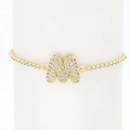 Detailed macro view of 18k gold plated tennis chain bracelet with crystal letter M pendant - Letter M