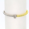 Detail of two-tone gold and silver beaded bracelet with a micro-paved zircon U-shaped charm - Letter U