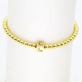 Detail eines 18 Karat vergoldeten Perlenarmbandes mit quadratischem Buchstaben-L-Anhänger - L