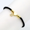 Macro detail of black braided rope bracelet with golden heart and paved letter D charms - Letter D