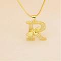 Macro shot of gold letter R pendant with micro-pave crystals and a small bee detail - Letter R