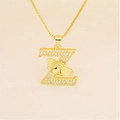 Macro detail of gold letter Z pendant necklace with pave zircons and a small honey bee - Letter Z