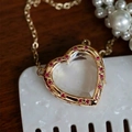 Pendentif cœur doré avec gemmes rouges et chaîne fine sur un fond de bois rustique - Collier en Verre Zirconia Violet Cœur (Médaillon Vide)