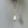 Makroansicht des Eiscreme-Anhängers mit Barockperle und goldfarbenen Metalldetails - Einfacher Eiscreme Stil / Gold