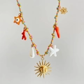 Macro shot of colorful woven rope necklace with sun, starfish, and pearl charms - Sun Orange Rope Style