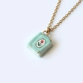 Dettaglio del ciondolo a libro in ceramica verde menta con motivi floreali rossi - Stile Libro Verde Menta Fiore Rosso