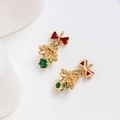 Macro detail of 14k gold plated Christmas bell charms with red bows and green zircon gems - Colored Zirconia / 18K Gold