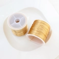 Two rolls of 14K gold filled beading wire for jewelry making on a white display tray - Gold (0.4mm / 100m)