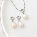 Detailed macro view of 18K natural freshwater pearl pendants and chain on white tray - Silver