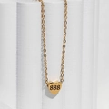 Detail of gold heart pendant with 888 engraving on a white display column - Style 888