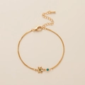 Detail van de gouden armband met bloemhanger en kleine blauwe zirkoon edelsteen - Armband / Maart Narcis Armband