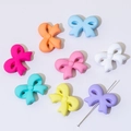 Close-up of colorful bow-shaped silicone beads with a needle showing DIY threading - Straight Hole Bowtie (32*24mm)
