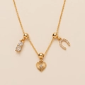 Detail view of gold necklace featuring horseshoe and starburst heart zircon pendants - Horseshoe Heart - Gold
