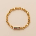 Golden beaded bracelet for girls with rainbow rhinestone rectangle charm on beige surface - Pencil