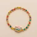 Detail of beaded bracelet with rainbow cake charm, gold beads and colorful enamel - Rainbow Cake Style / Book