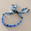 Detail van blauwe rondelle stenen kralen en paisley stoffen strik op een unieke ketting - Blauwe Kralenketting