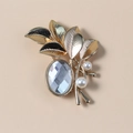 Detailed close-up of a gold leaf brooch with an oval crystal and white pearls - White KC Gold
